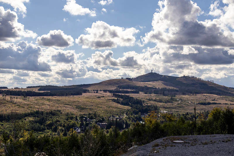 Panoramablick vom Bahnhof Schierke im Harz auf die weite Landschaft mit Fichten und Wiesen, im Hintergrund der Gipfel des Brockens mit dem Sendeturm.