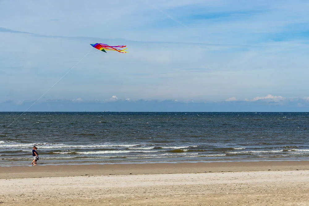 Ein bunter Drachen fliegt über dem Strand von Langeoog an der Nordsee.