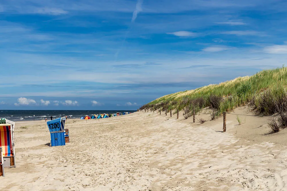 Sandstrand und Dünenlandschaft auf Langeoog mit Strandkörben entlang der Nordsee.