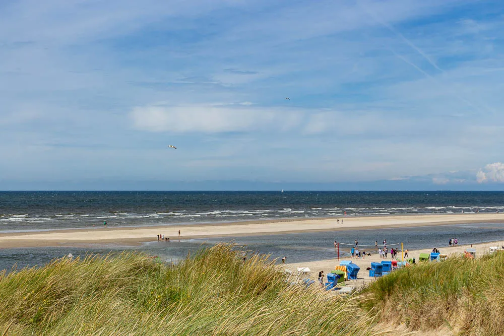 Blick von den Dünen auf den Strand von Langeoog mit Strandkörben und der Nordsee.