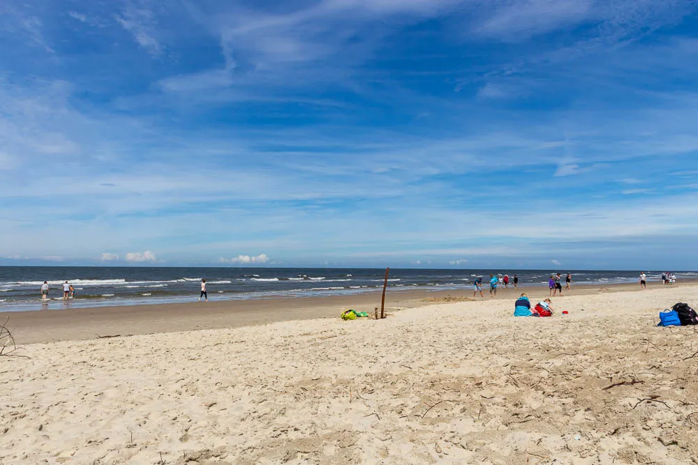 Menschen spazieren am Strand von Langeoog entlang der Nordsee.